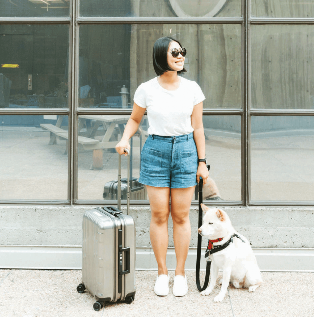 Woman smiling with suitcase and dog